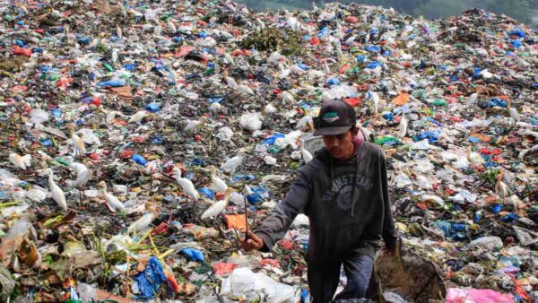 A scavenger collects plastic waste to sell to a recycling centre at a landfill