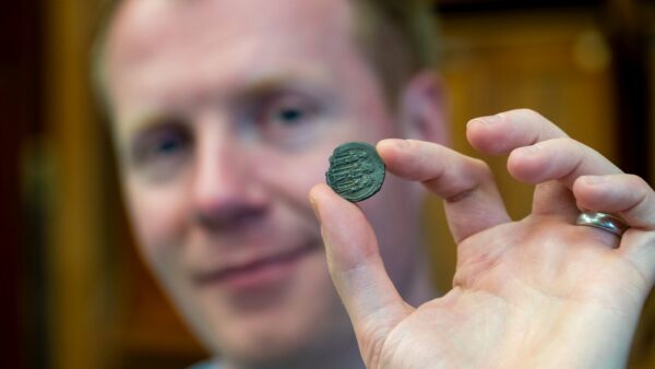 A man holds an 1200-year-old silver coin