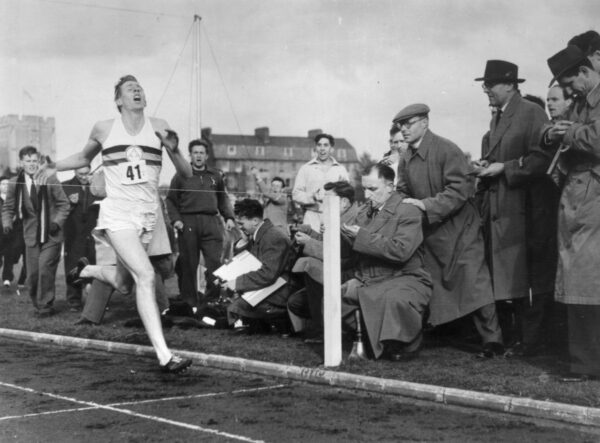 A black and white photo of Roger Bannister crossing a finish line